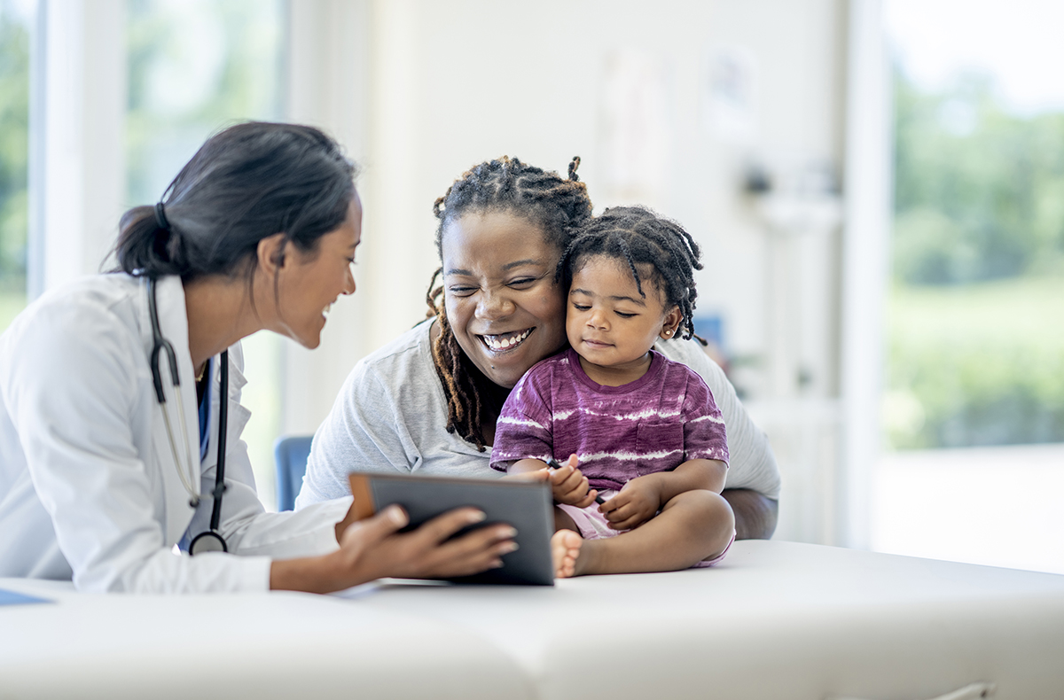Image of mother and child patient revewing ipad with physician