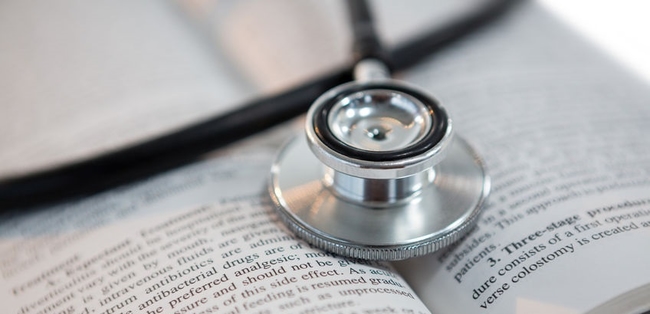 stethoscope lying on open-faced book