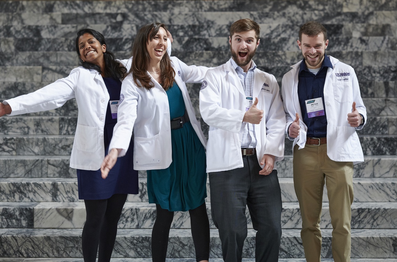 Early career physicians smiling in front of steps