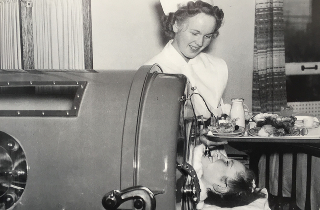 polio patient in iron lung and nurse with tray of food