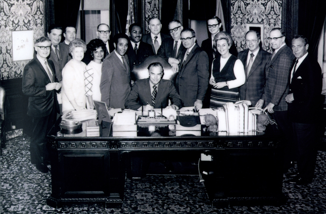 Gov. Dan Evans signs Senate Bill 182. MEDEX Founder Richard Smith, MD, stands to the governor's right.