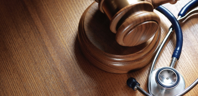 gavel and stethoscope resting on wooden table
