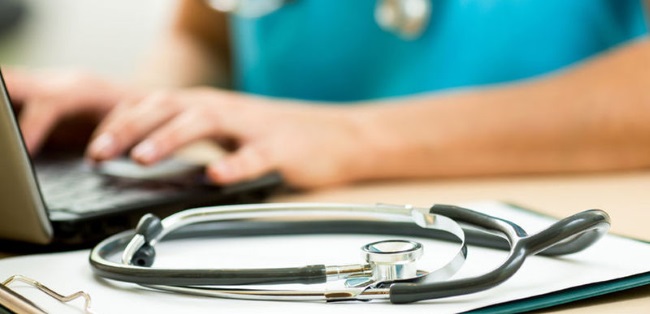 physician working at laptop with stethoscope on the desk