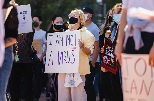 protester with 'I am not a virus' sign