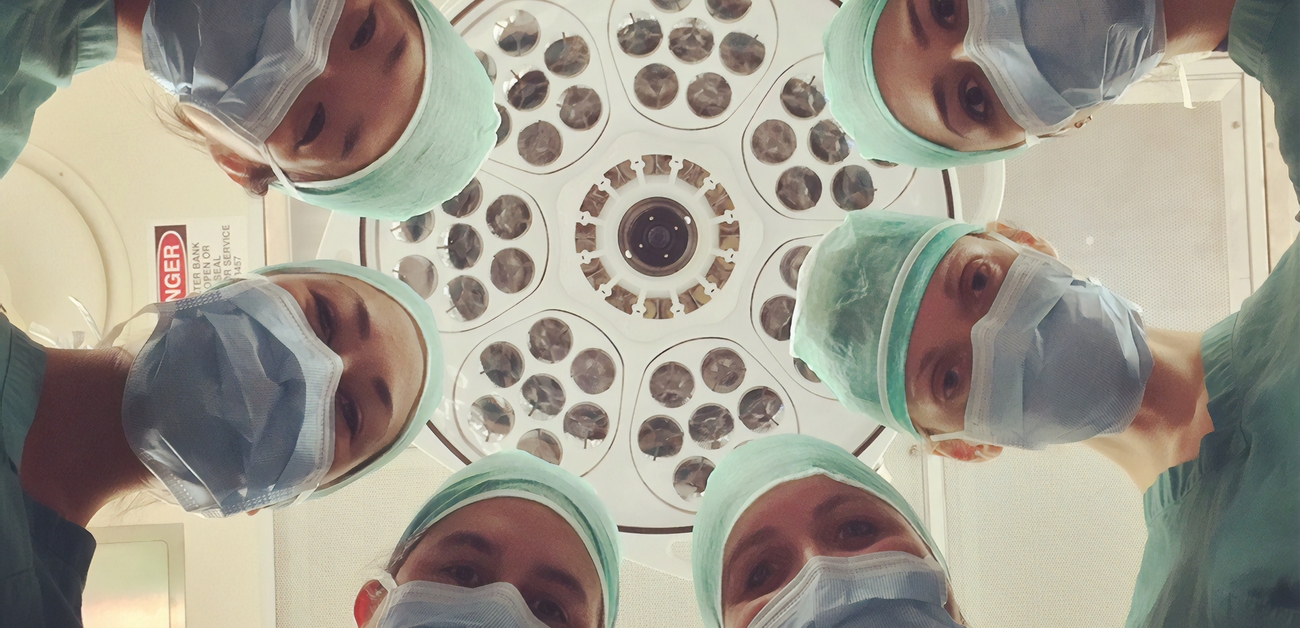surgeons staring down at patient on operating table