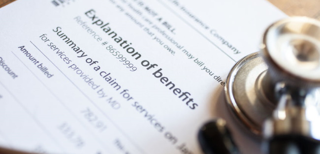stethoscope lying on a explanation of insurance benefits paper