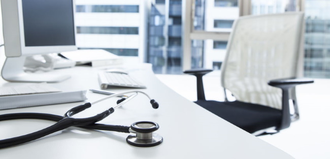 stethoscope on office desk next to a computer